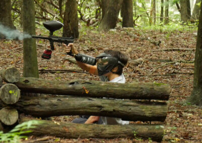 paintball player behind logs