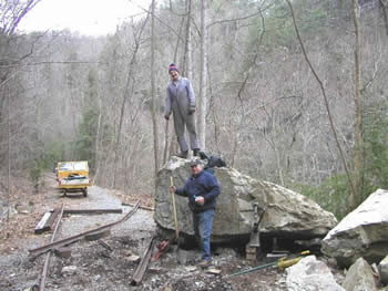 workers removing huge rock from tracks