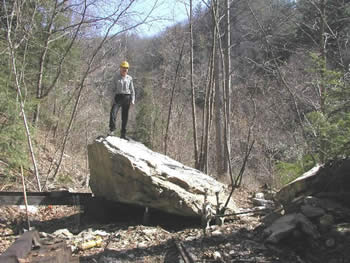 man standing on huge rock fallen on tracks