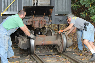 men rolling railcar wheels