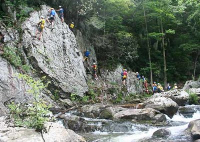 climbers on rock face above river