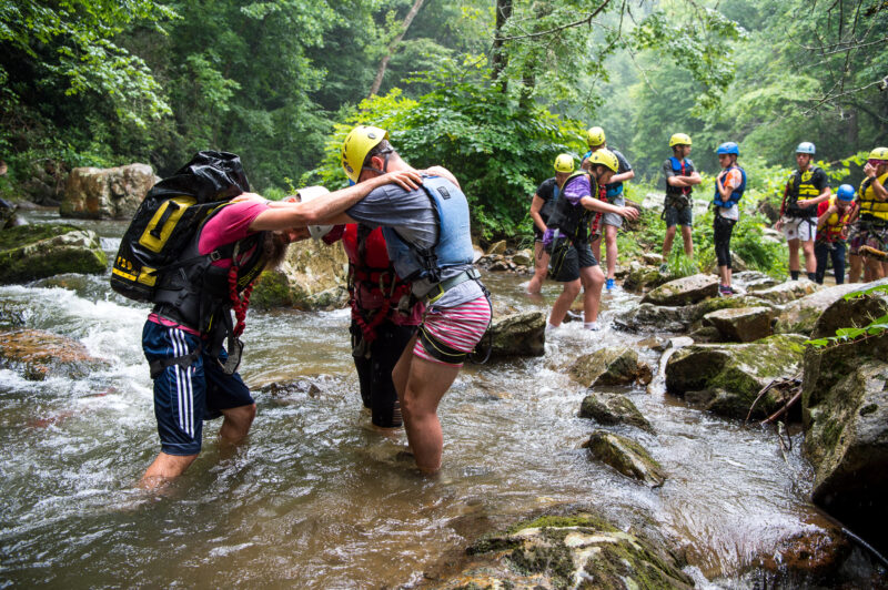 three people linking arms to cross rapid river