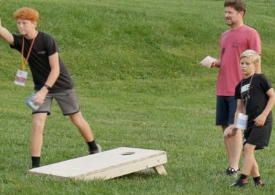 dad and sons playing corn hole