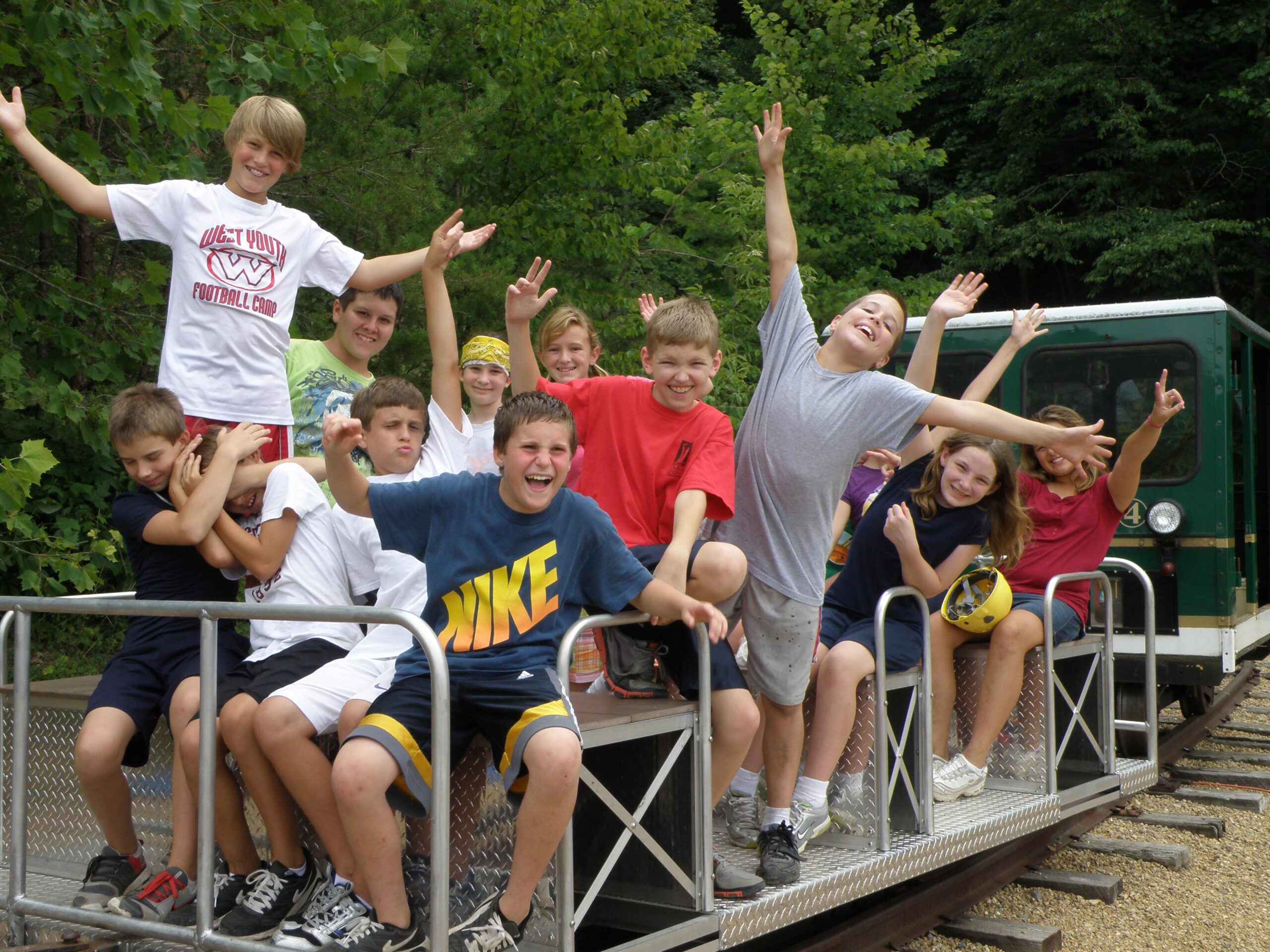 group of smiling, waving kids on rail car